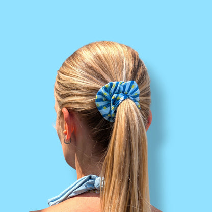 Chouchou Riviera Limone&Sole en satin bleu à rayures et motifs soleils porté dans une queue-de-cheval blonde