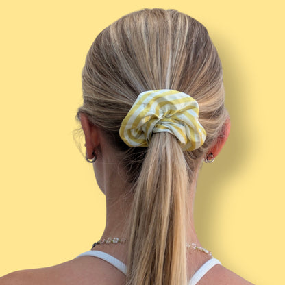 Chouchou Limone&Sole Limonata en satin rayé jaune et blanc porté en queue de cheval sur des cheveux blonds
